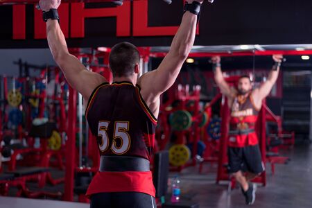 Hard Core Bodybuilding. Muscular athletic bodybuilder fitness model training arms with dumbbells in...