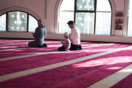 Group of muliethnic religious muslim young people  praying an dreading Koran together. Group of muslims praying in the mosque.の写真素材