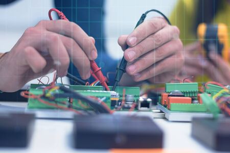 Two young handsome engineers working on electronics components.Tech tests electronic equipment in service center. Technologically Advanced Scientific Research Center.の写真素材