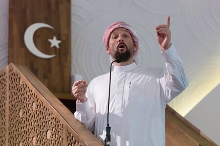Muslims young arabic Imam has a speech on friday afternoon prayer in mosque. Muslims have gathered for the friday afternoon prayer in mosque and are listening to the speech of imamの写真素材