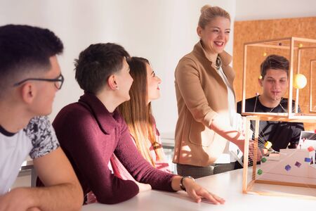 emale Architecture teacher at work. Female professor explain architectural projects to students. Beautiful female university architecture professor explain lessons to multiethnic students.の写真素材
