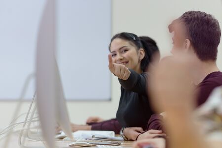 Happy female student showing thumbs up, smiling diverse young female student looking at camera with...