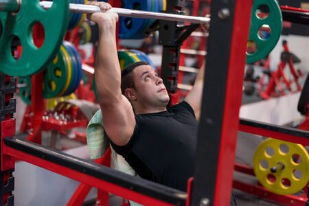 Hard Core Bodybuilding. Muscular athletic bodybuilder fitness model training arms with dumbbells in...