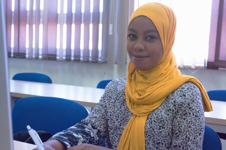 Beautiful female muslim african american IT student looking and smiling into camera.の写真素材
