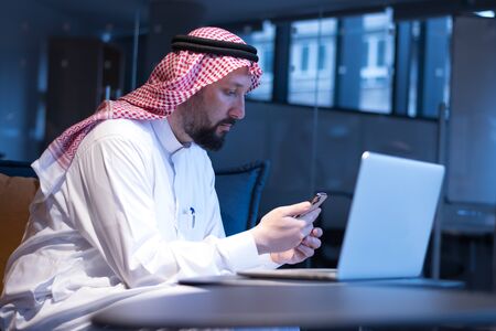 A Middle Eastern businessman typing on the phone in his office. Businessman Arabic using mobile phone for connection to communication.Business Technology concept.の写真素材