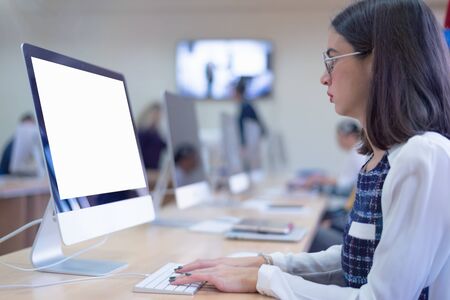 Beautiful female  IT student working at her computer lab.  Female student listening lesson from their professor. Education and technology concept.の写真素材