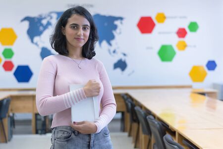 Beautiful female eastern IT student looking and smiling into camera.