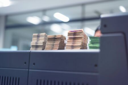 Bundles of banknotes divided into groups with currency straps placed on the electronic counting machineの写真素材