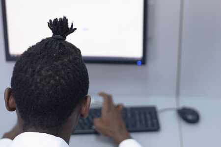 An african american IT student in the computer lab. Students listening lesson from his teacher.