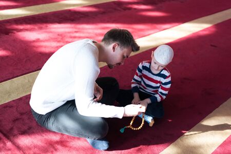Muslim father and son praying together. Muslim dad and son praying in the mosque.の写真素材