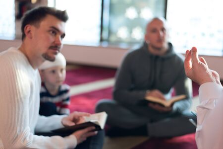 Group of muliethnic religious muslim young people praying and reading Koran together inside beautiful modern mosque.の写真素材