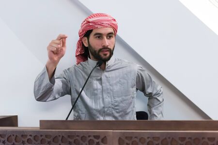 Muslims young arabic Imam has a speech on friday afternoon prayer in mosque. Muslims have gathered...