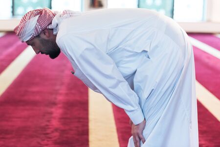 Young Arabic Muslim man  praying. Doing a dailly pray inside modern beautiful mosque.