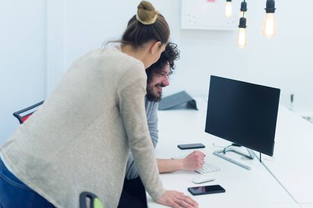 Business team working on new project and smiling. Man and woman sitting together in modern office for project discussion.の写真素材