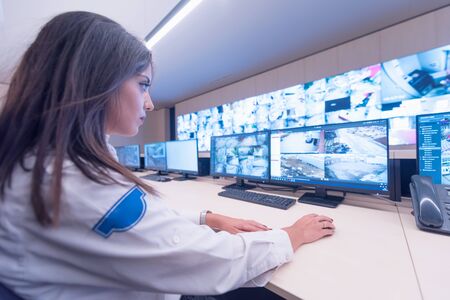 Security guard monitoring modern CCTV cameras in surveillance room. Female security guard in surveillance room.の写真素材