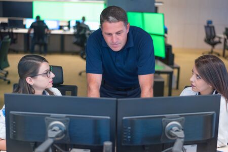 Security guard monitoring modern CCTV cameras in surveillance room. Group of  Female security guards...