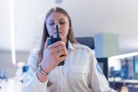 Security guard monitoring modern CCTV cameras in surveillance room. Female security guard in...