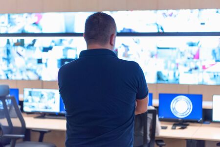 Security guard monitoring modern CCTV cameras in surveillance room.  Male security guard in...