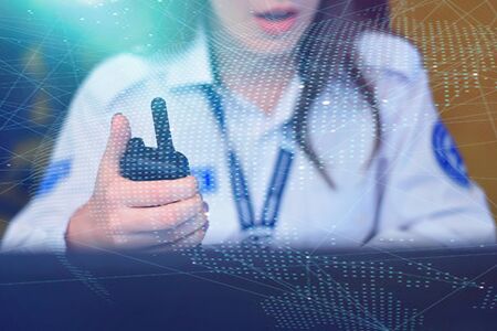 Female security guard operator talking on the phone, calling in the alarming event to the external team of field force agents.の写真素材