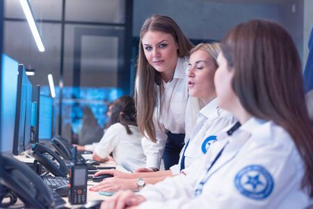 Group of security guards working on computers while sitting in the main control room, CCTV...
