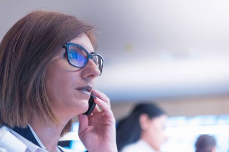 Female security guard operator talking on the phone, calling in the alarming event to the external team of field force agents.の写真素材