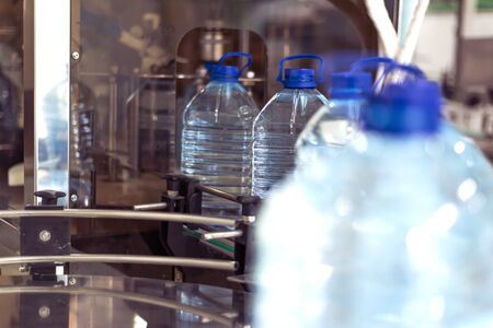 Bottling plant - Water bottling line for processing and bottling pure spring water into blue bottles. Selective focus.の写真素材