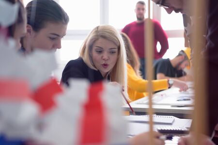 Beautiful young female teacher helping a student during class. Female Professor Holding Lecture to...