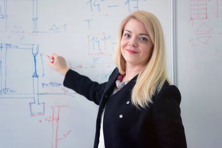 Beautiful young female teacher helping a student during class. Female Professor Holding Lecture to Multi Ethnic Group of Students. Smart Young People Studying at the University.の写真素材