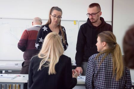 Female Architecture teacher at work. Female professor explain architectural projects to students. Beautiful female university architecture professor explain lessons to multiethnic students.の写真素材