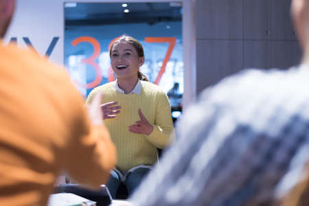 Handicapped young woman with colleagues working in office. She is smiling and passionate about the workflow. Performing in co-working space. Office people working together.の写真素材