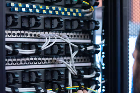 An Expert Engeneer in datacenter server room  connecting cables in server cabinet in network server room.の写真素材