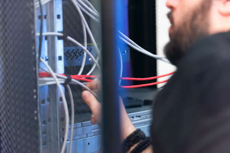 An Expert Engeneer in datacenter server room  connecting cables in server cabinet in network server...