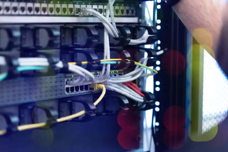 An Expert Engeneer in datacenter server room  connecting cables in server cabinet in network server...