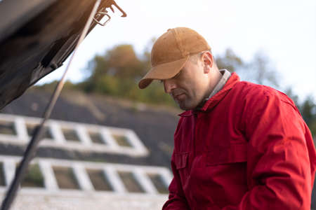 Emergency roadside assistance, road assistance worker in uniform trying to fix car breakdown or engine failure.  Roadside assistance conceptの写真素材