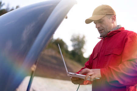 Emergency roadside assistance, road assistance worker in uniform trying to fix car breakdown or...
