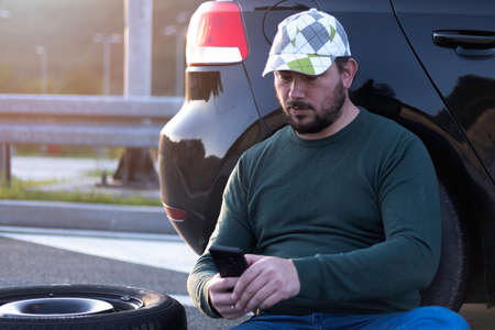 Man calling road assistance on the highway. Calling car service, assistance or  tow truck while having troubles with his car.の写真素材