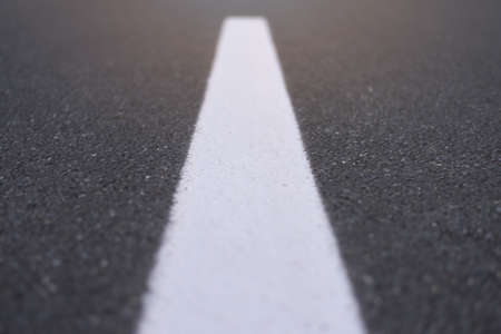 White dividing line perspective over dark asphalt, highway road marking. Abstract transportation background textureの写真素材