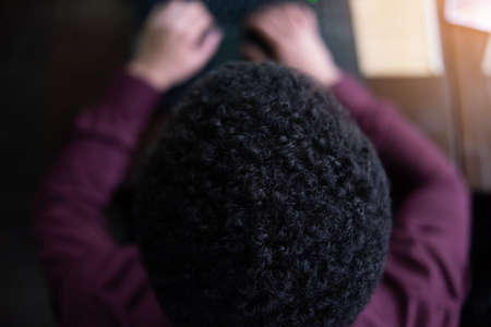 Young black male  developer sitting in pizza restaurant, drinking coffee or  tea and working with laptop.の写真素材