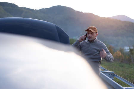 Frustrated and angry man calls roadside assistance by phone. car problem. Roadside assistance...