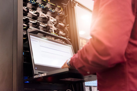 Young it engeneer business man with thin modern aluminium laptop in network server room. Young it engeneer in datacenter server roomの写真素材