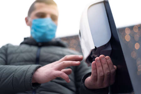 Restaurant's or hotel's guest using hands disinfection in front of restaurant or hotel during pandemicの写真素材