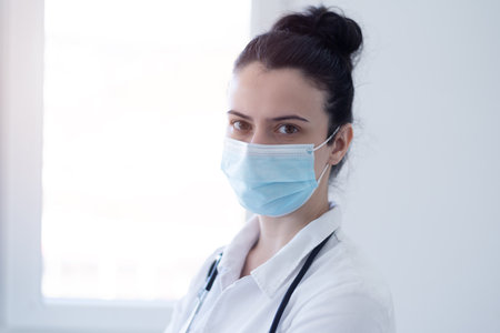 Female doctor wearing protective mask and looking into camera  during pandemic.の写真素材