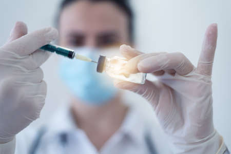 General practitioner vaccinating  patient in clinic. Doctor giving injection to senior woman at...