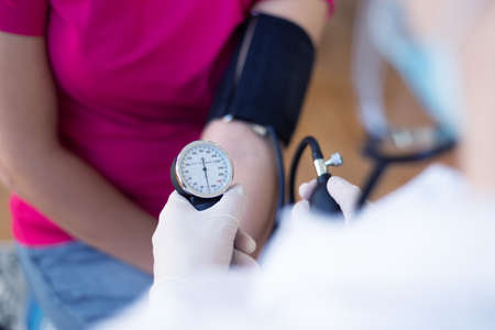Female doctor using sphygmomanometer with stethoscope checking blood pressure to a patient in the hospitalの写真素材