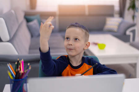 Distance learning and online education. Schoolboy boy studies at home and does school homework....