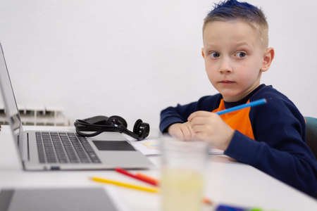 Distance learning and online education. Schoolboy boy studies at home and does school homework....