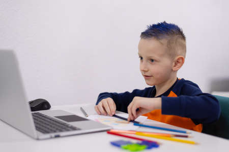 Distance learning and online education. Schoolboy boy studies at home and does school homework....