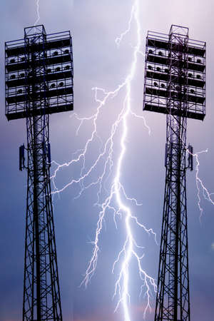 Spotlights on a lighting mast over the stadium against the blue sky with white clouds on a dayの写真素材