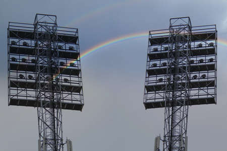 Spotlights on a lighting mast over the stadium against the blue sky with white clouds on a dayの写真素材