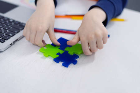 Little schoolboy holding puzzle pieces and trying to solve itの写真素材